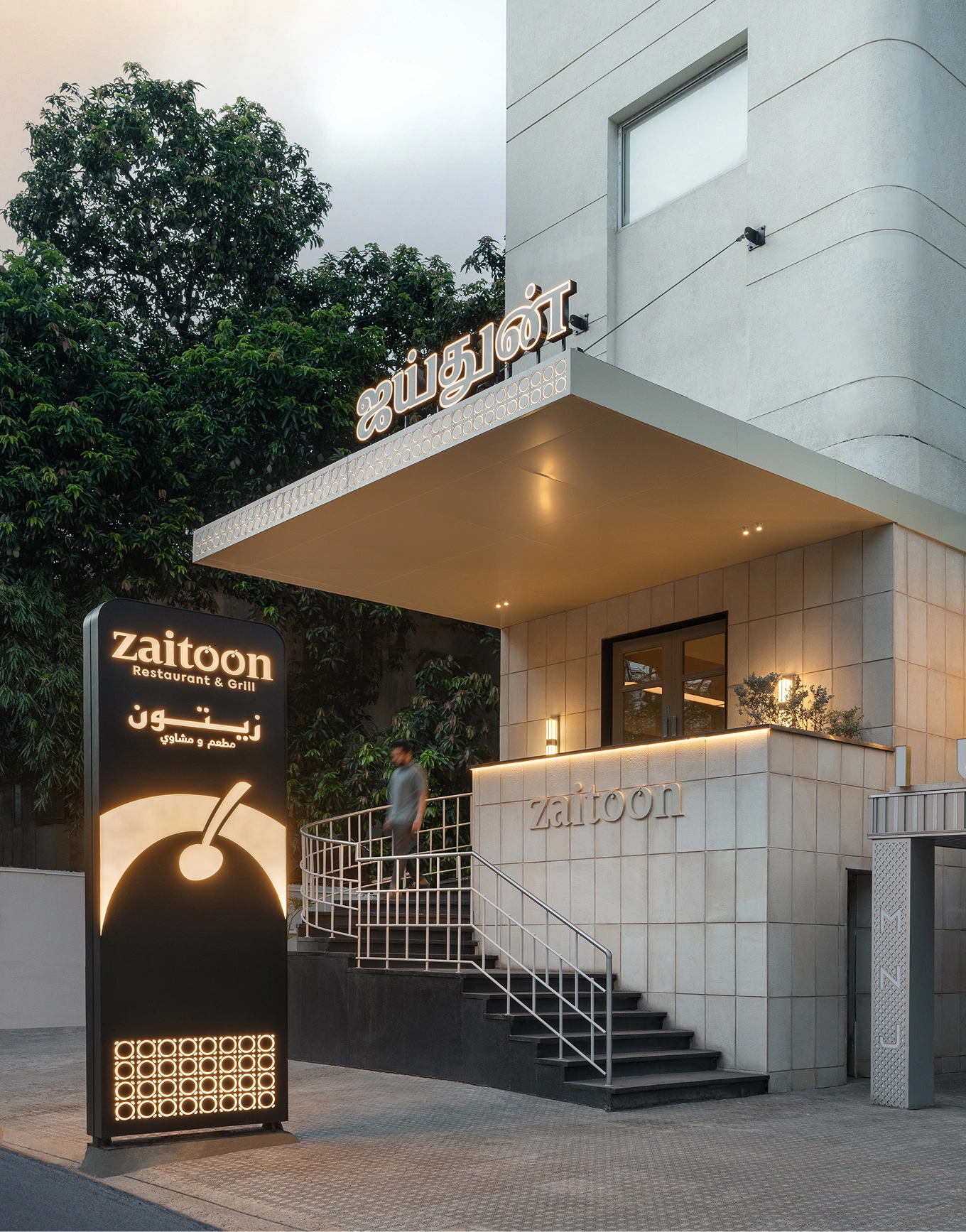 Exterior entrance of Zaitoon Restaurant & Grill with illuminated signage and staircase